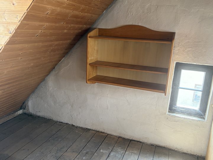 Giebelseite mit kleinem Fenster und Wandregal