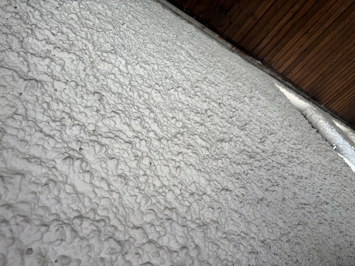 Wanddetail: rauer Strukturputz, darüber die Holzdecke (wird durch Rigips ersetzt)